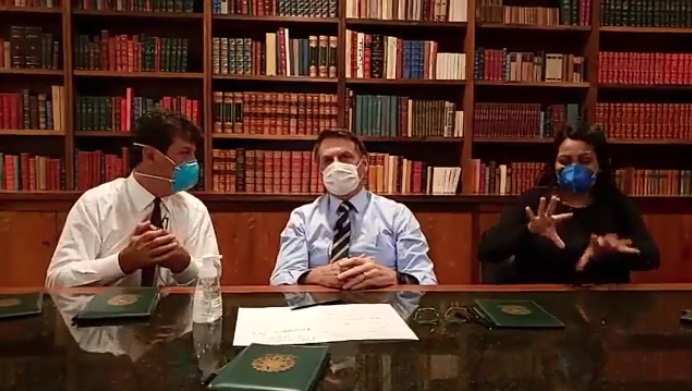 Presidente em pronunciamento nas redes sociais usando máscara dias após sugerir que vírus era alarme sem fundamento. Imagem Reprodução.