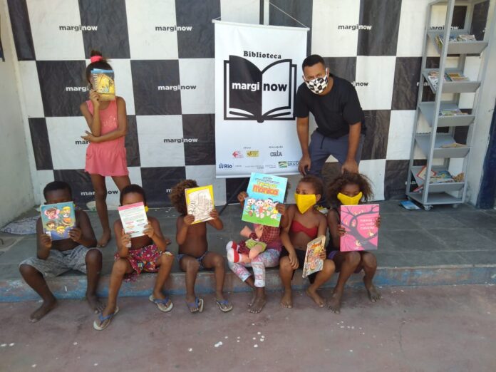 O escritor Jessé Andarilho, idealizador da biblioteca Marginow, junto a crianças da favela Antares