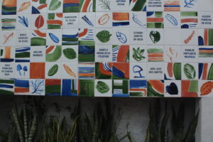 Painél em azulejo com tipos botânicos e nomes de vítimas, residentes da Maré, da COVID19.